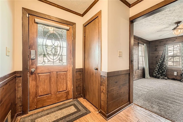 foyer entrance with a textured ceiling, wooden walls, and wainscoting