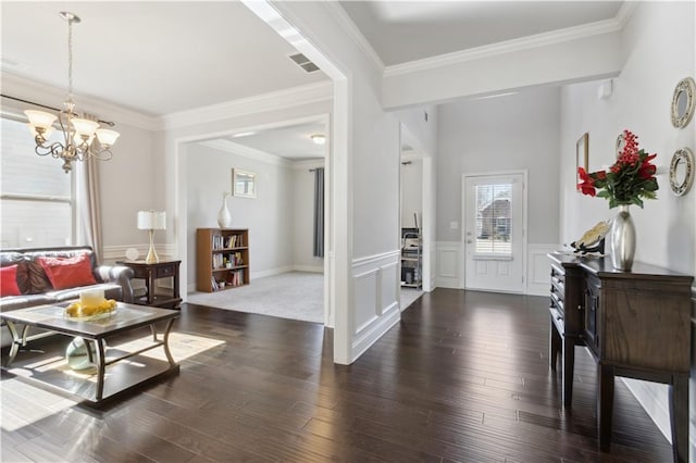 foyer with a wainscoted wall, dark wood-style flooring, visible vents, and crown molding