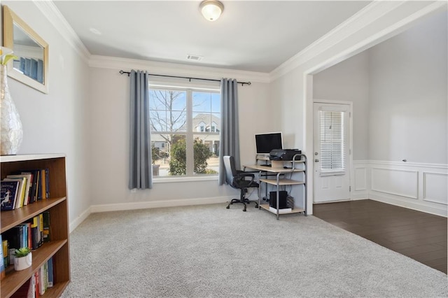 office area featuring a wainscoted wall, visible vents, dark colored carpet, and crown molding