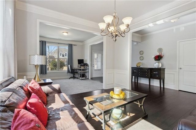 living area with wainscoting, dark wood-style floors, ornamental molding, a chandelier, and a decorative wall