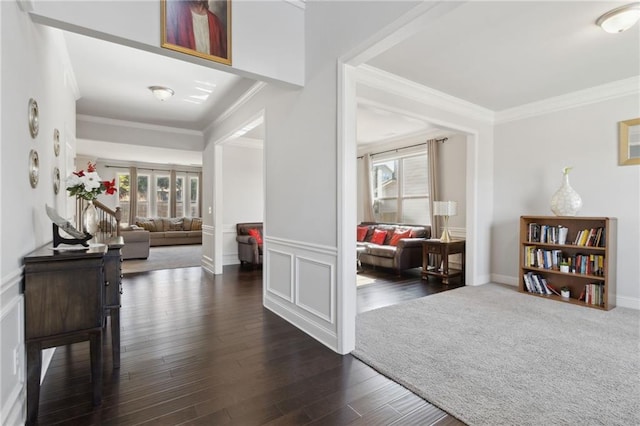 foyer with ornamental molding, dark wood-style flooring, and a wainscoted wall