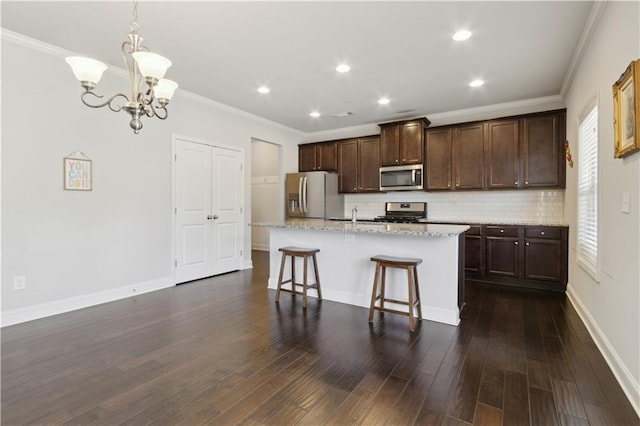 kitchen featuring dark wood-style floors, appliances with stainless steel finishes, a breakfast bar, hanging light fixtures, and a kitchen island with sink