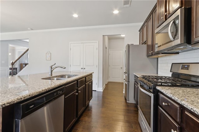 kitchen featuring light stone counters, a sink, visible vents, ornamental molding, and appliances with stainless steel finishes