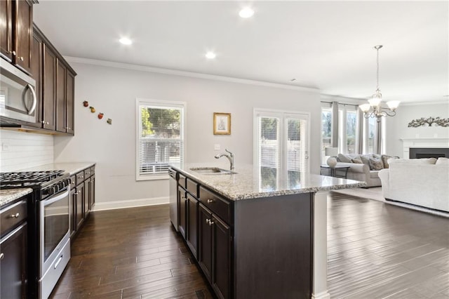 kitchen featuring a center island with sink, appliances with stainless steel finishes, open floor plan, a sink, and dark brown cabinets