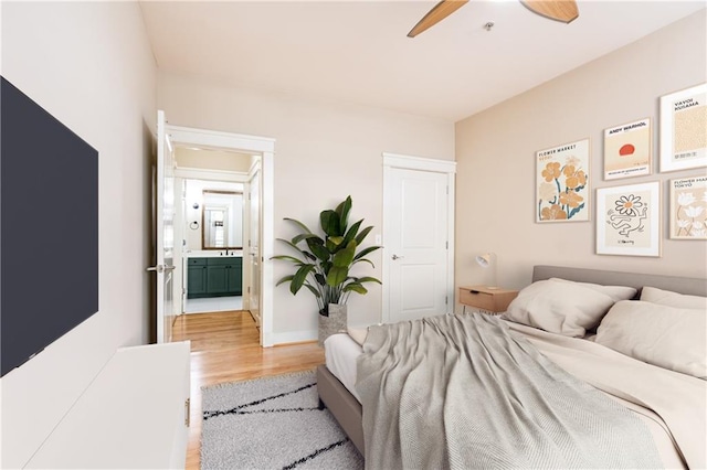 bedroom with connected bathroom, ceiling fan, and light hardwood / wood-style flooring