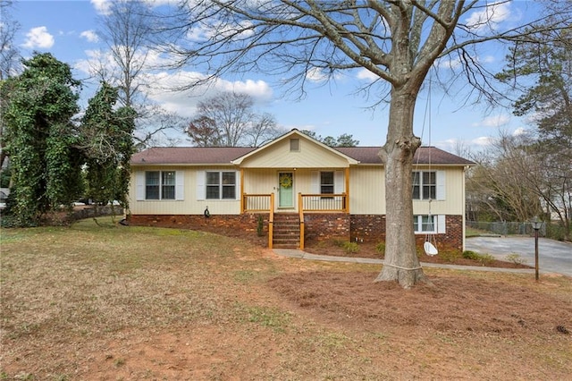 single story home featuring brick siding, covered porch, and a front yard