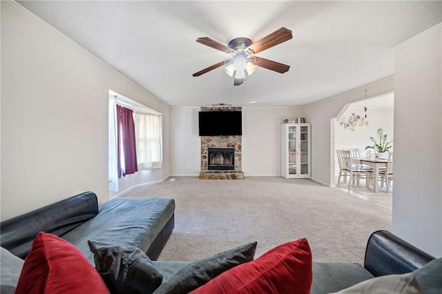 carpeted living room with ceiling fan, ornamental molding, and a fireplace