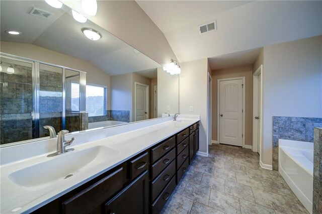 bathroom with vanity, independent shower and bath, and vaulted ceiling