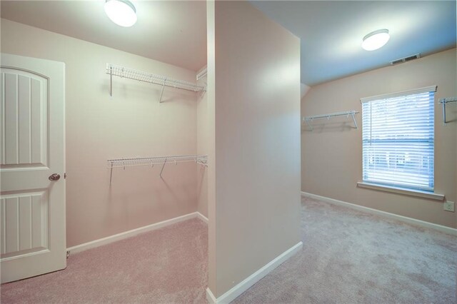 walk in closet with light carpet and vaulted ceiling