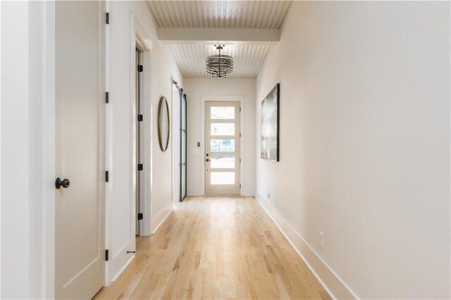 doorway featuring light wood-style flooring, baseboards, and a barn door