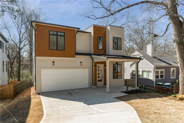 modern home with a garage, concrete driveway, and fence