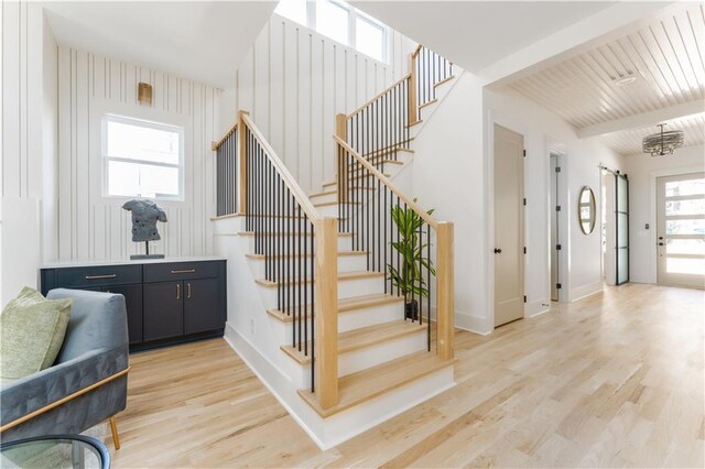 stairs featuring a barn door, wood finished floors, beam ceiling, and baseboards