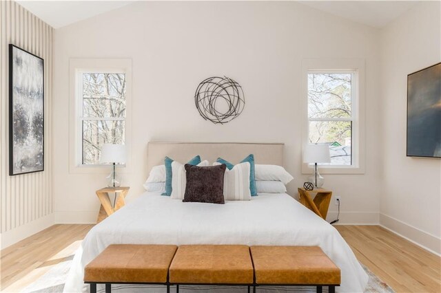 bedroom featuring lofted ceiling, baseboards, and wood finished floors