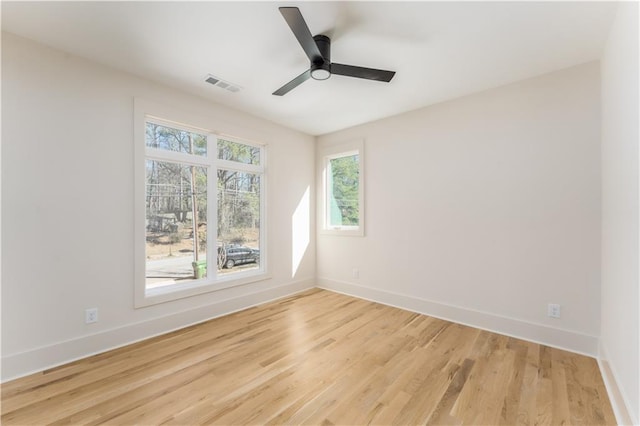 unfurnished room with a ceiling fan, light wood-type flooring, visible vents, and baseboards