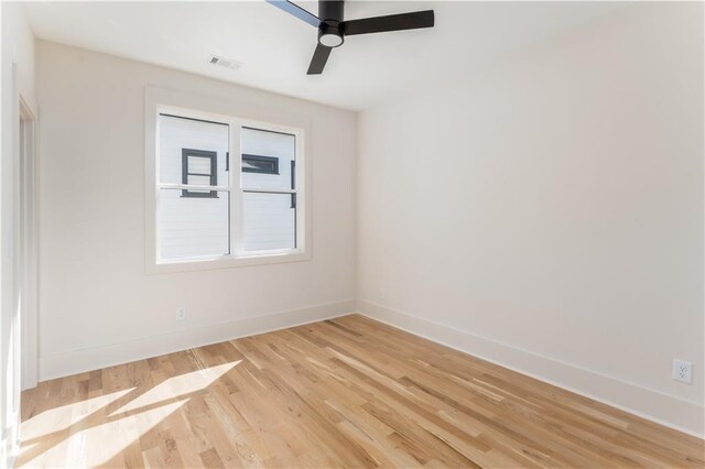 empty room featuring light wood-type flooring, visible vents, baseboards, and ceiling fan