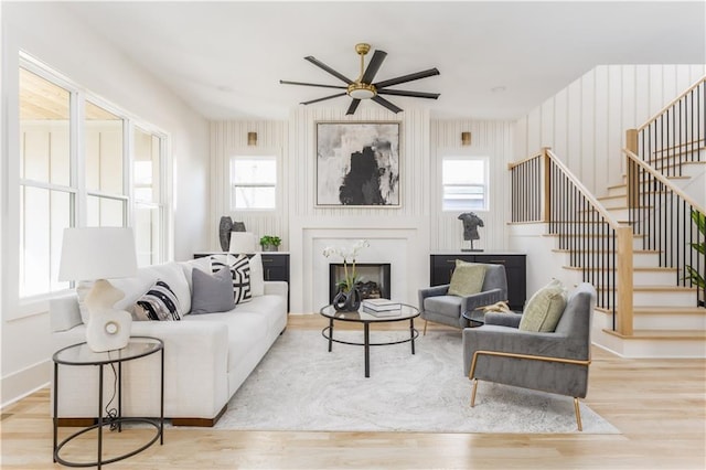 living room with ceiling fan, stairway, wood finished floors, and a high end fireplace