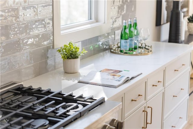 interior details featuring tasteful backsplash, white cabinets, and stove