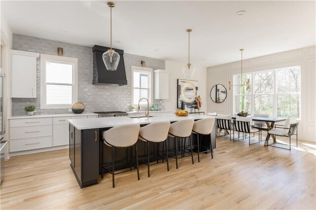 kitchen featuring a wealth of natural light, white cabinets, a sink, and wall chimney exhaust hood