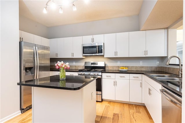 kitchen featuring a kitchen breakfast bar, stainless steel appliances, sink, white cabinets, and a center island