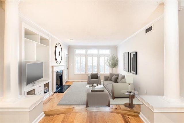 living room with light wood-type flooring, a premium fireplace, and crown molding