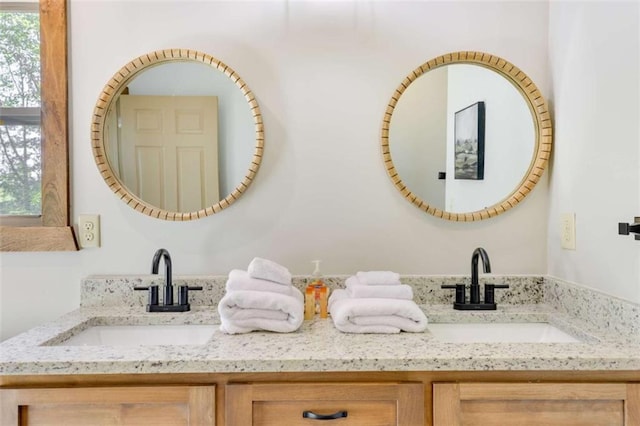 bathroom with double vanity, a sink, and a healthy amount of sunlight