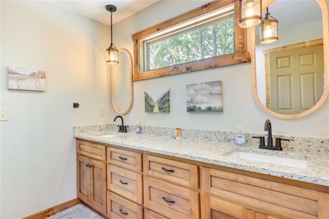 bathroom with double vanity, a sink, and baseboards