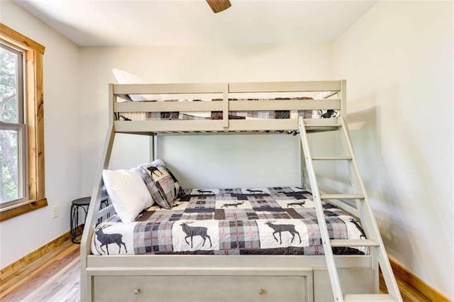 bedroom featuring multiple windows, wood finished floors, and baseboards