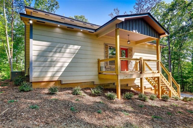 back of house with stairs and board and batten siding