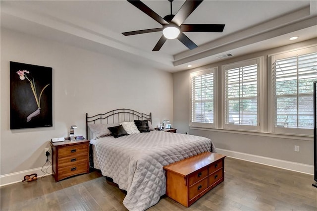 bedroom with baseboards, recessed lighting, a raised ceiling, and wood finished floors