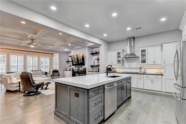 kitchen with white cabinetry, a sink, wall chimney exhaust hood, and a center island with sink