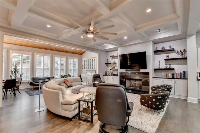 living area with a tile fireplace, coffered ceiling, wood finished floors, and beamed ceiling