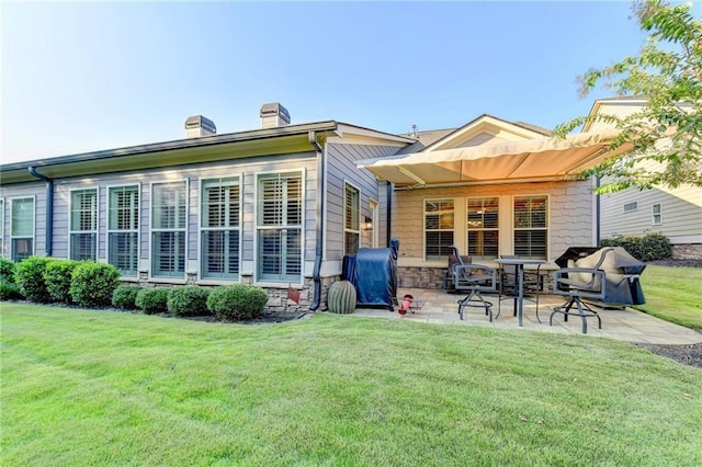 back of property featuring a chimney, a yard, and a patio area