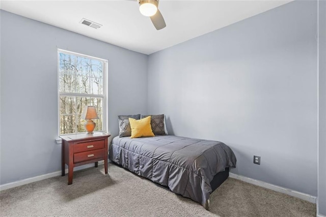 carpeted bedroom featuring a ceiling fan, visible vents, and baseboards