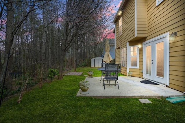 yard at dusk featuring an outbuilding, a patio, and a storage unit