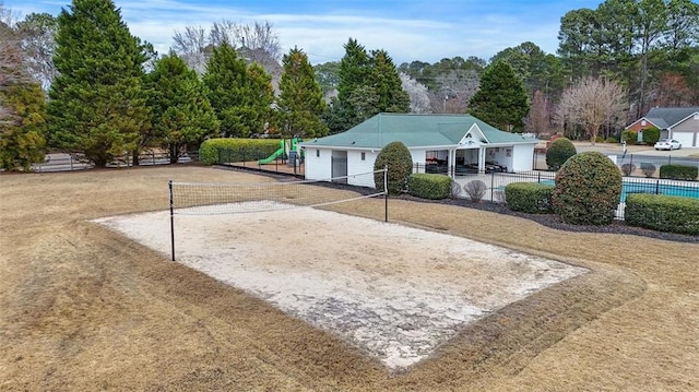 view of property's community featuring driveway, fence, a playground, and volleyball court