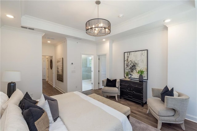 bedroom featuring a tray ceiling, ensuite bathroom, dark wood-type flooring, and a notable chandelier