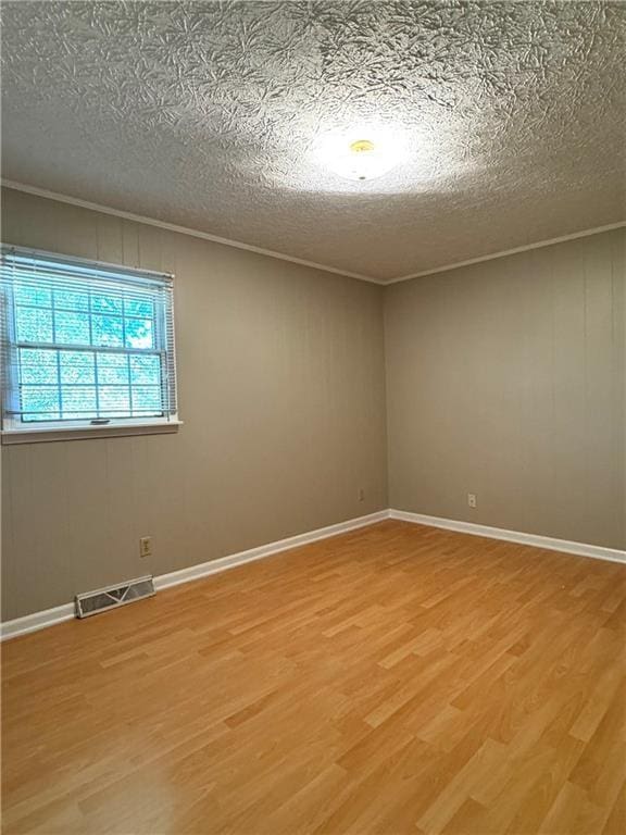 unfurnished room with hardwood / wood-style floors, crown molding, and a textured ceiling