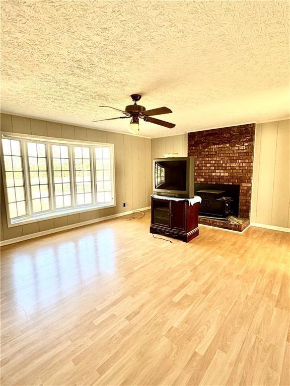 unfurnished living room featuring ceiling fan, a textured ceiling, and light hardwood / wood-style flooring