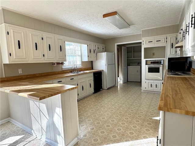 kitchen with white refrigerator, a textured ceiling, butcher block countertops, wall oven, and washing machine and clothes dryer