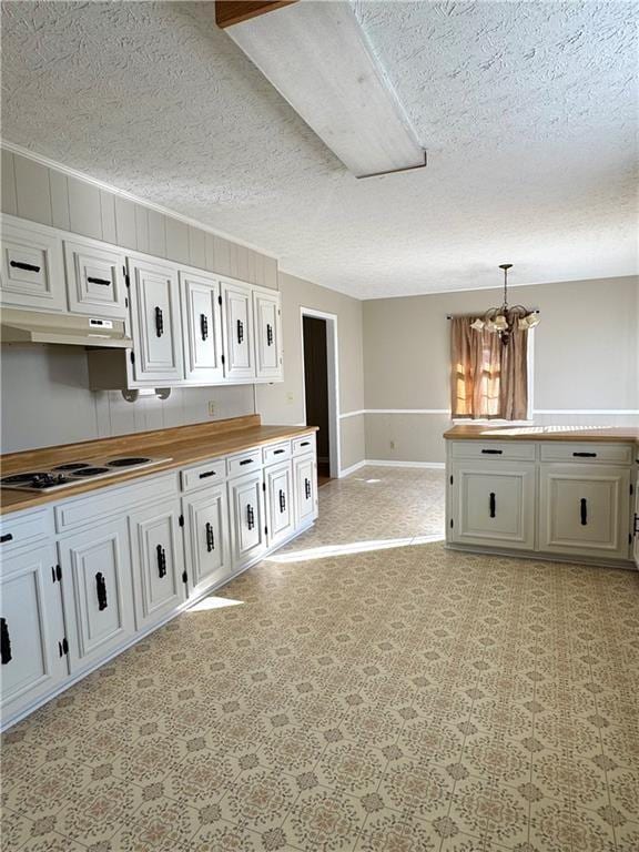 kitchen with a textured ceiling, white stovetop, white cabinets, a chandelier, and hanging light fixtures