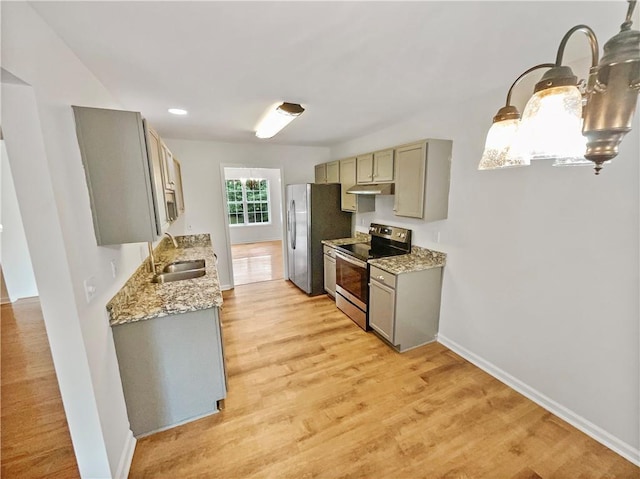 kitchen with gray cabinets, appliances with stainless steel finishes, light wood-type flooring, light stone countertops, and sink