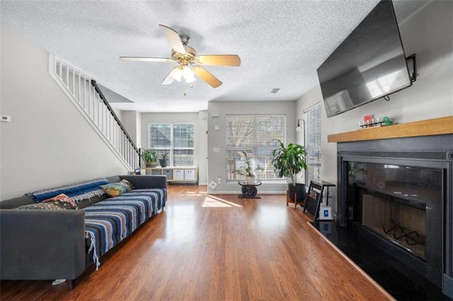 living room with hardwood / wood-style floors, a textured ceiling, and ceiling fan