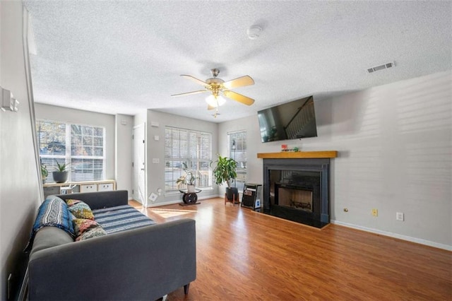 living room featuring wood-type flooring, ceiling fan, and a textured ceiling