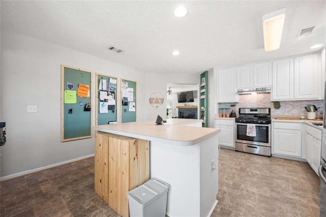 kitchen with gas range, a center island, white cabinets, and decorative backsplash