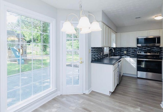 1391 Warrenton Hunt, Lawrenceville, GA 30043 - kitchen with appliances with stainless steel finishes, dark countertops, white cabinetry, decorative backsplash, and a chandelier