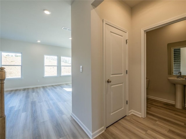 hallway with light hardwood / wood-style flooring and sink