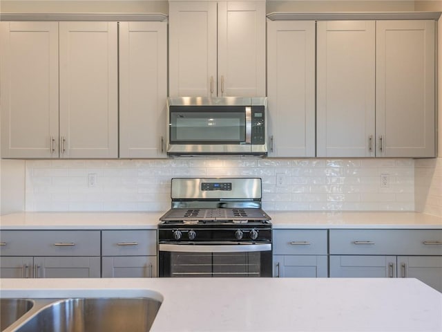 kitchen with tasteful backsplash, gray cabinets, and appliances with stainless steel finishes