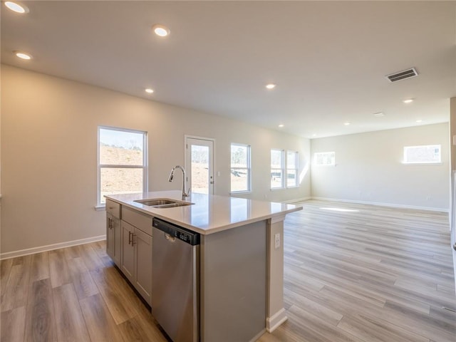 kitchen featuring dishwasher, light wood-type flooring, a kitchen island with sink, and sink