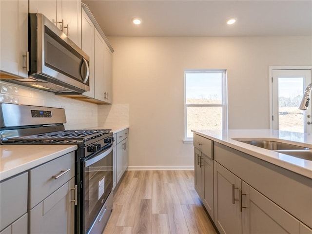 kitchen with gray cabinets, sink, stainless steel appliances, and light hardwood / wood-style flooring