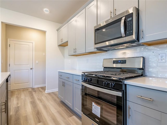 kitchen featuring appliances with stainless steel finishes, light wood-type flooring, tasteful backsplash, and gray cabinets